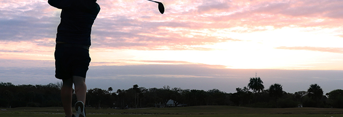 golfer taking a swing at sunset